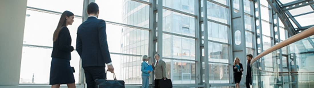 People in suits walking past a large window.