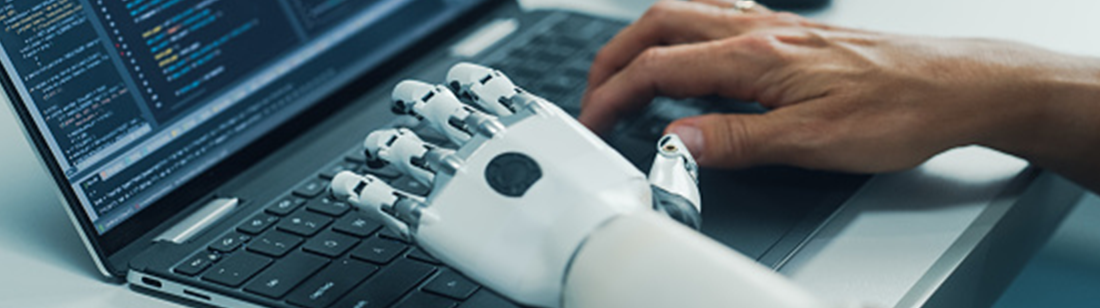 Two hands, one prosthetic, typing at a keyboard.